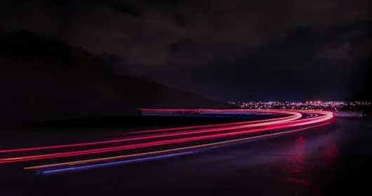 Light trails on road against night sky