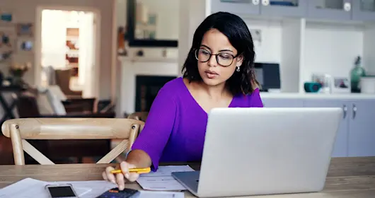 Woman sitting at a table with laptop and mobile phones