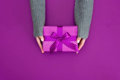 gift in female hands on a colored background