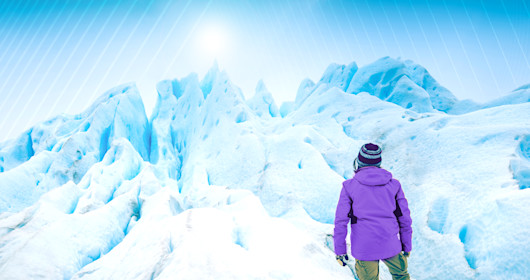 person standing below snow covered mountains