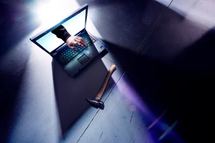 黑客的手从笔记本电脑屏幕伸出来，正在打字