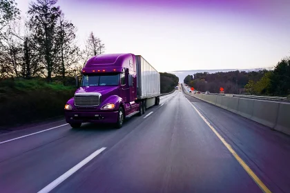 18轮紫色半挂车在黄昏的高速公路上