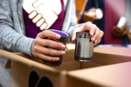 Volunteer packing tin cans into cardboard box