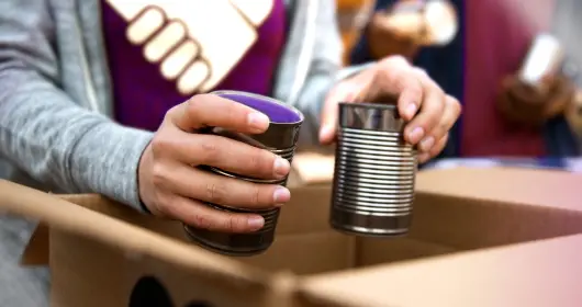 Volunteer packing tin cans into cardboard box