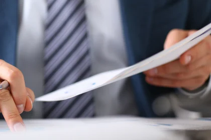 Close up of sheet of paper being reviewed by man in suit and tie