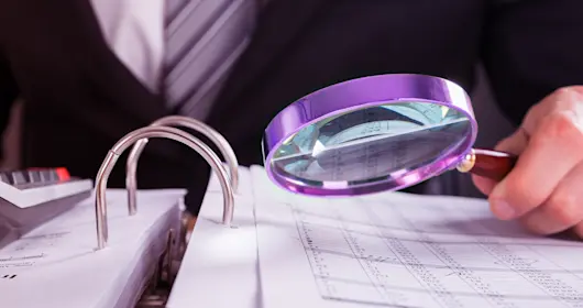 Businessman examining an invoice with a magnifying glass