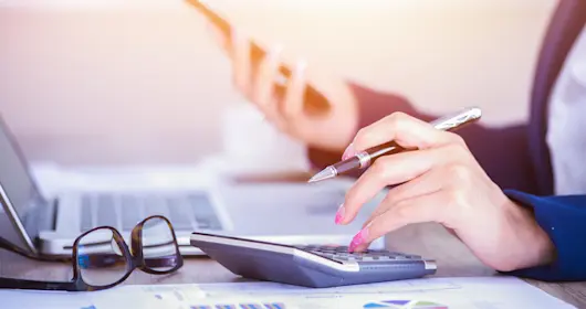 Business woman using calculator with pen in hand