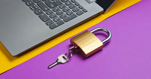 Padlock and key sitting next to open laptop