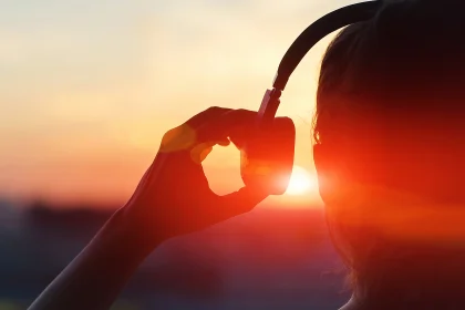 Person listening to headphones at sunset