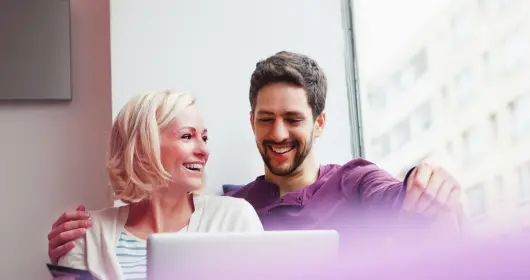 couple smiling in front of laptop computer