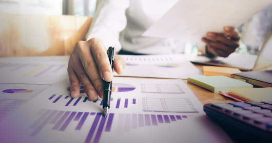 Midsection of businesswoman reading graphs on table