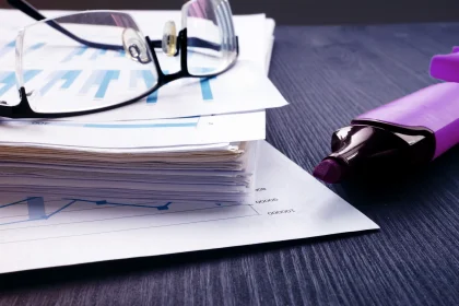 Stack of papers with financial reports and glasses