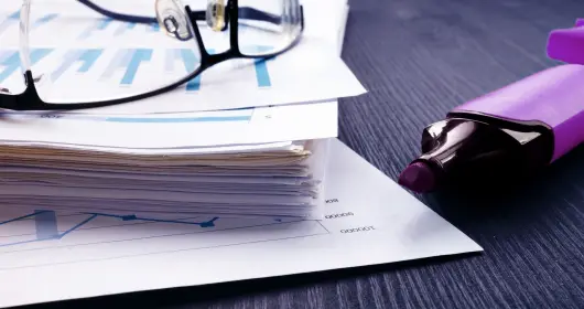 Stack of papers with financial reports and glasses