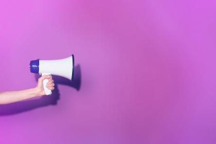 Person holding a megaphone in front of purple background