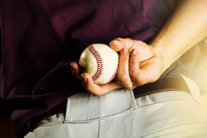 close up shot of a baseball pitcher holding a baseball behind his back