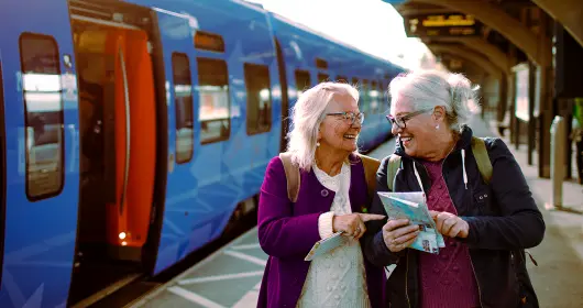 two elderly women laughing while waiting at the train station