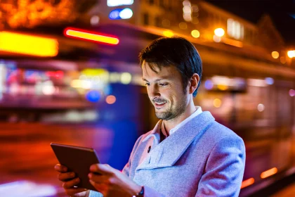 晚上在街上微笑着看数码平板电脑的商人肖像