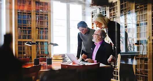 three coworkers having a discussion in library