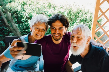 Smiling male caretaker taking selfie with senior man and woman