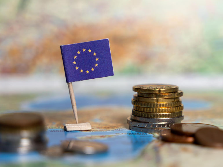 European union flag with stacks of coins on a map