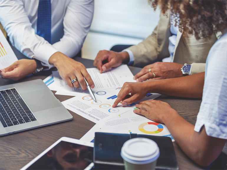Close up of people pointing to a graph with data