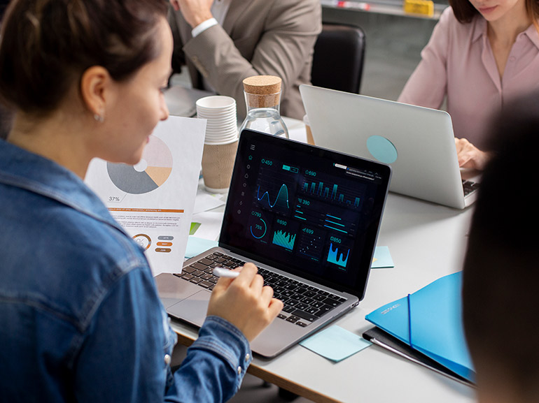 Team analysiert während einer Besprechung Geschäftsdaten mit Diagrammen und Grafiken auf Laptops.