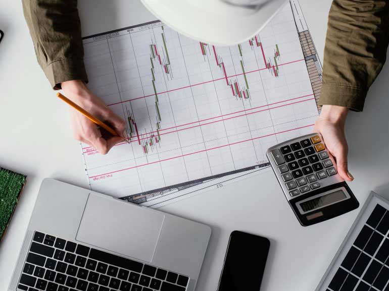 Women working on charts and holding a calculator