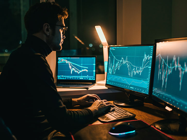 متداول يراقب الأسواق المالية على شاشات متعددة