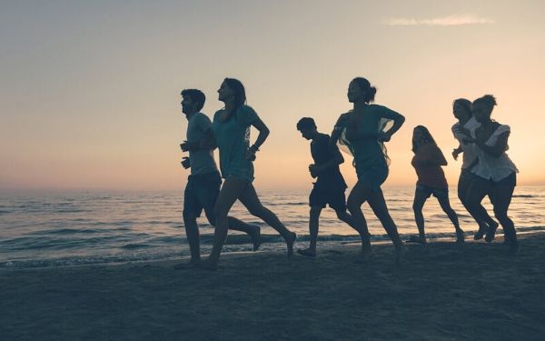 Group running together on a beach at sunset