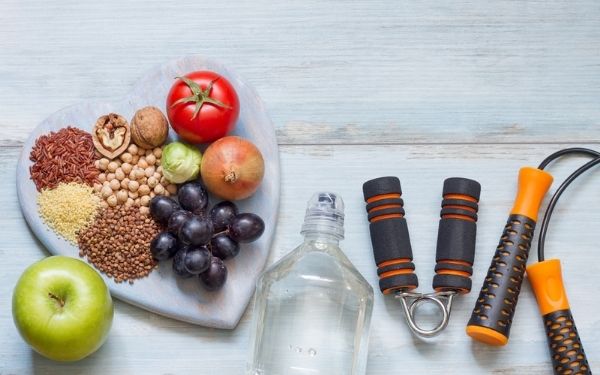 Healthy food on heart shaped board with water bottle and fitness gear 