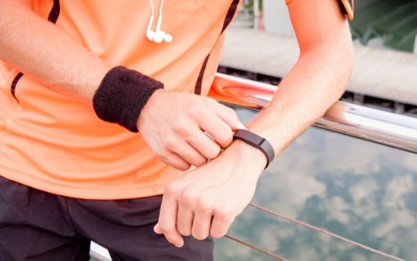man in an orange shirt checking a fitness watch