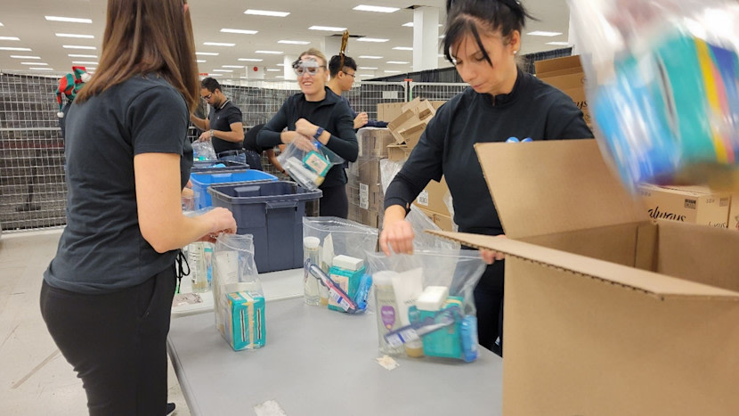A group of individuals in black attire is assembling boxes in a workspace.