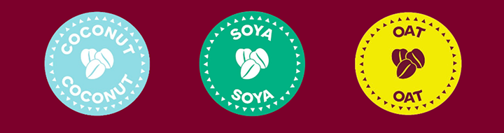 Three circular badges on a burgundy background: a blue “Coconut” badge, a green “Soya” badge, and a yellow “Oat” badge, each featuring a central coffee-bean icon.