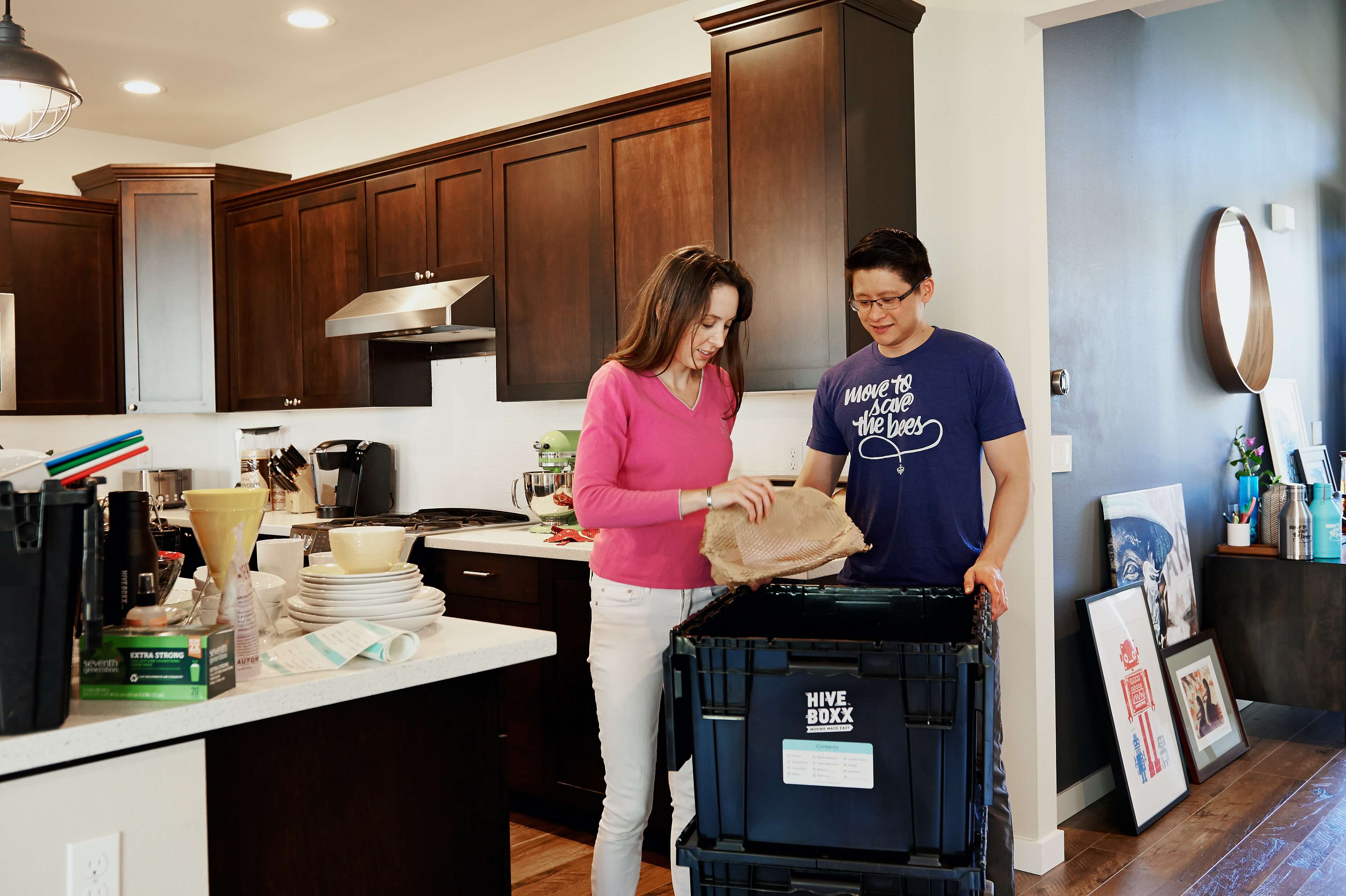 A man and woman packing their belongings in the kitchen