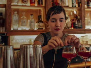 A bartender making a drink after finishing bartender training