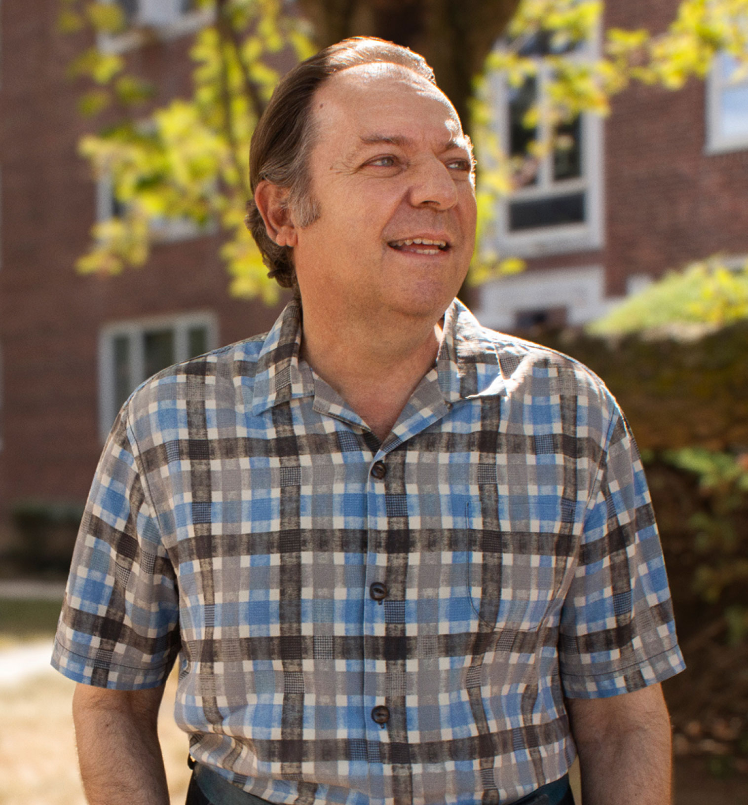 Image of a man wearing a plaid shirt and confidently looking off into the distance.