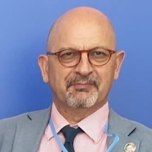 picture of author Remi Parmentier in grey suit jacket, pink shirt, blue tie and wearing glasses 