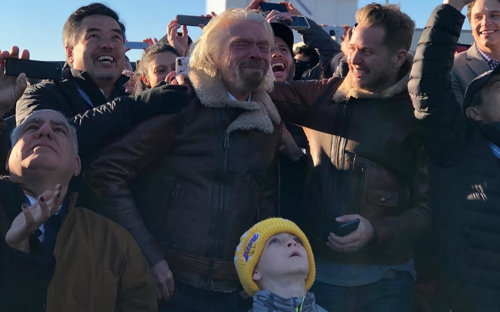 Richard Branson and Sam Branson celebrate with a crowd during Virgin Galactic's first spaceflight