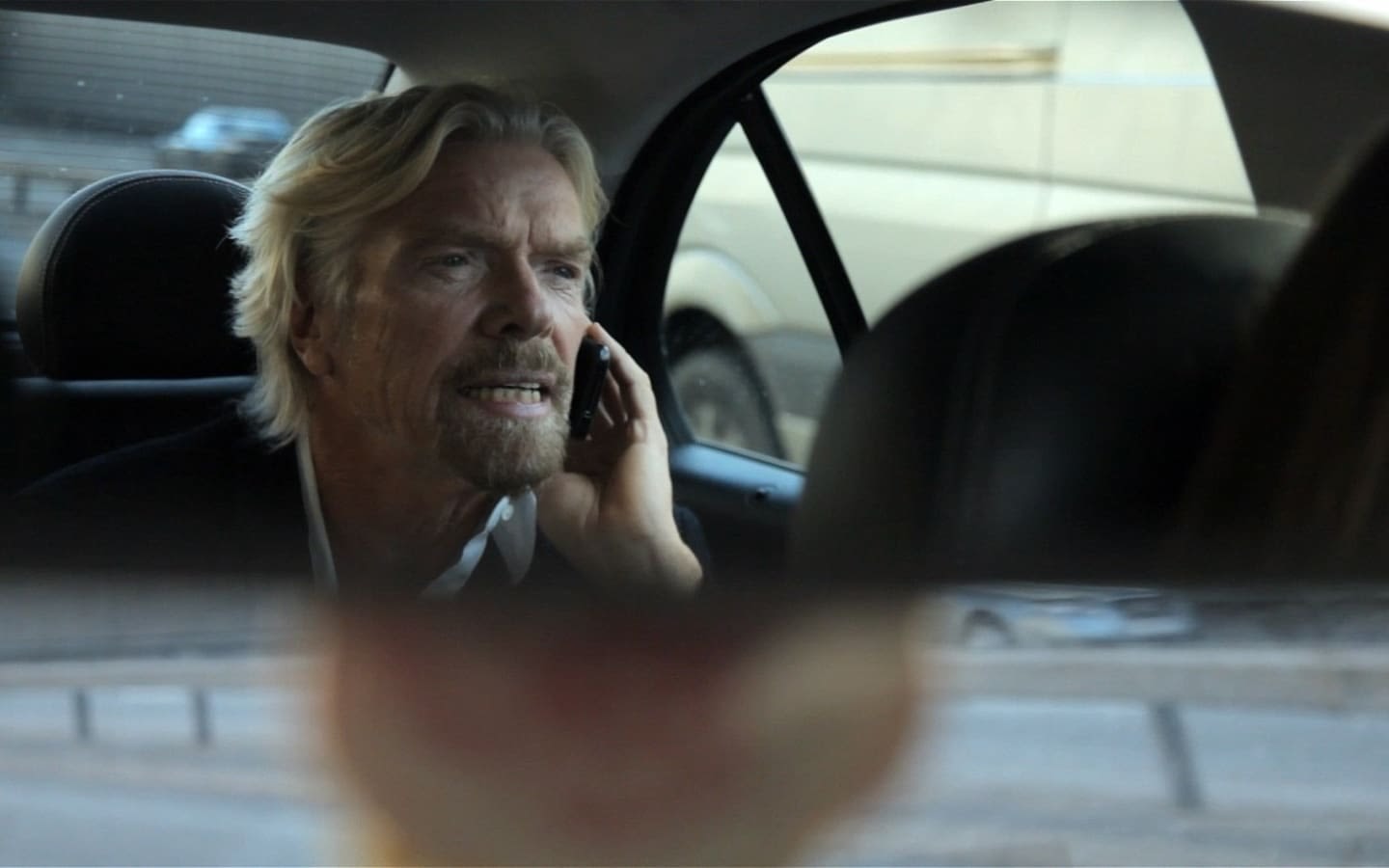 Richard Branson sitting in the back of a car on the phone