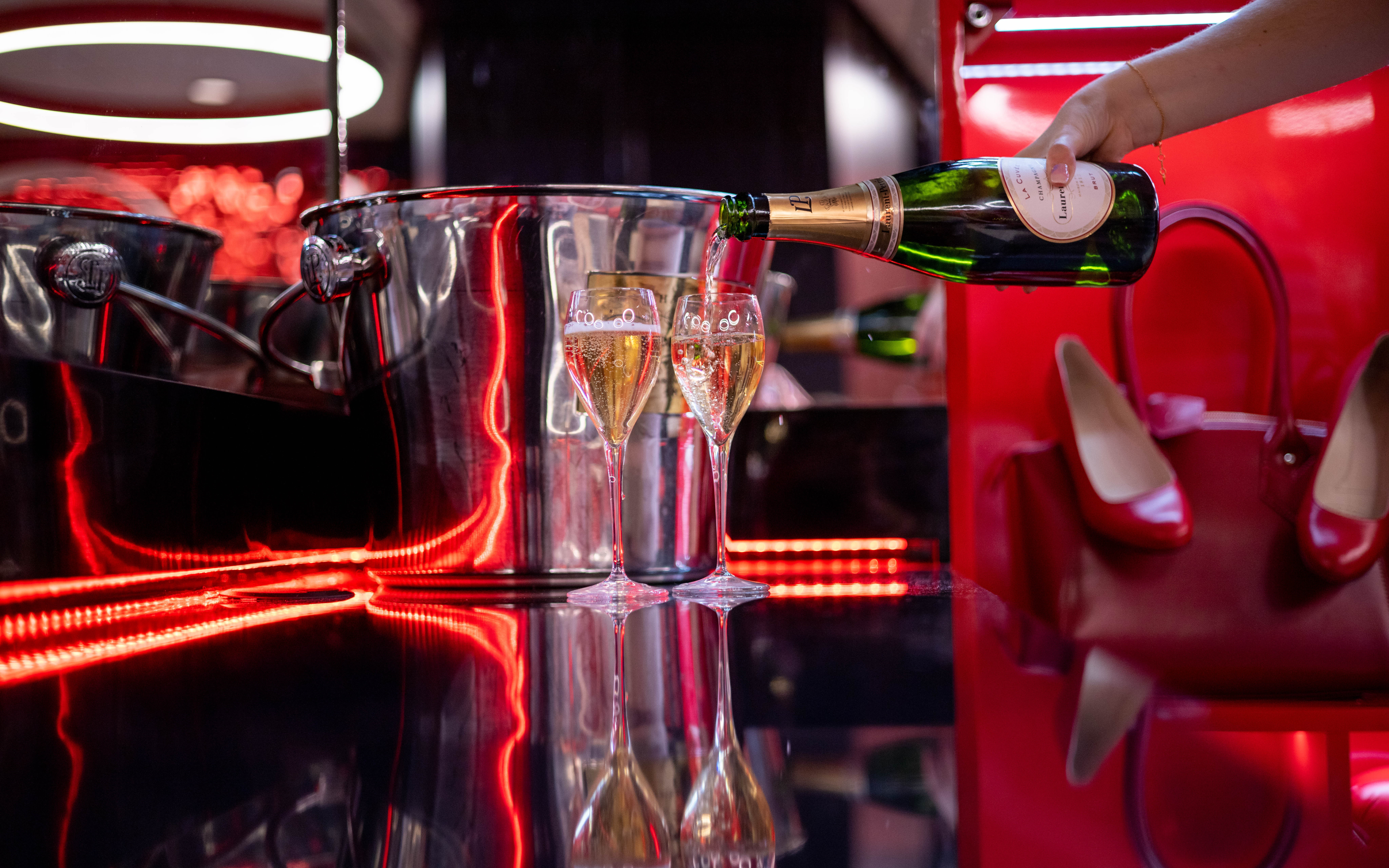 An image of champagne being poured into two glasses in the Virgin Red Room.