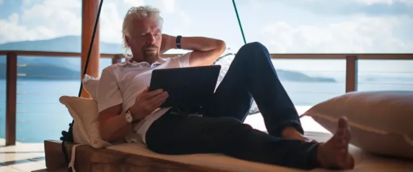 Richard Branson lying down and reading from his iPad on Necker Island