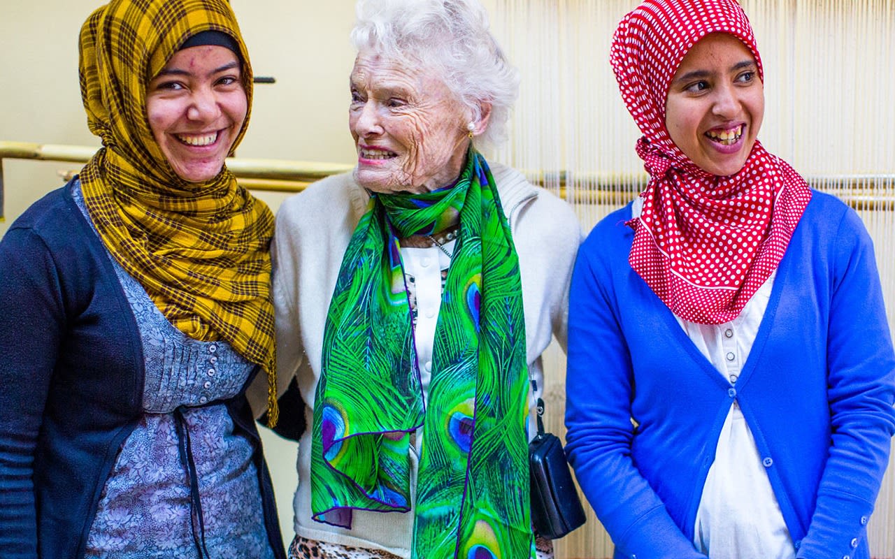 Eve Branson wearing a green scarf in between two ladies with red and yellow headscarves