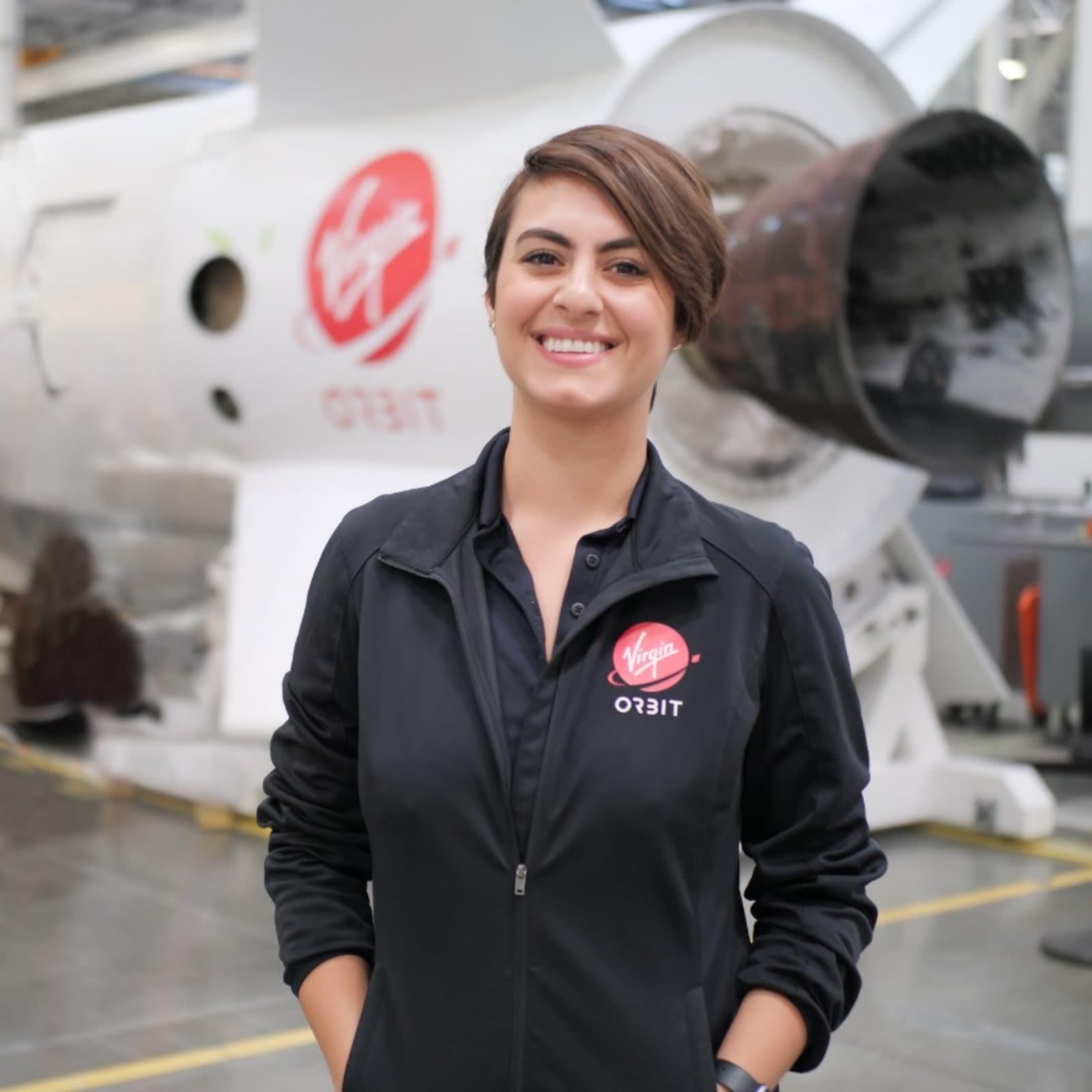 Diana Alsindy from Virgin Orbit smiling to the camera in her uniform 