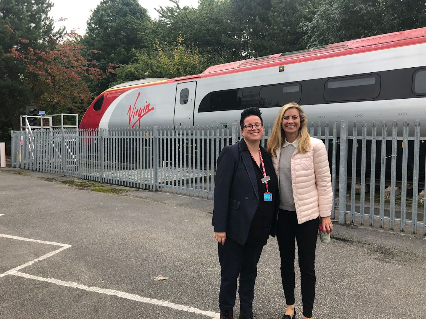 Holly Branson with Vic Whitehouse, smiling at the camera in front of a Virgin Train