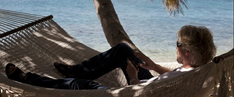 Richard Branson lying in a hammock with the sea in the background