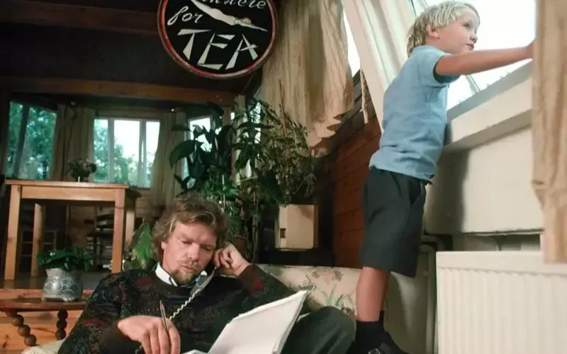 A young Richard Branson on the phone whilst a very young Sam Branson looks out the window 