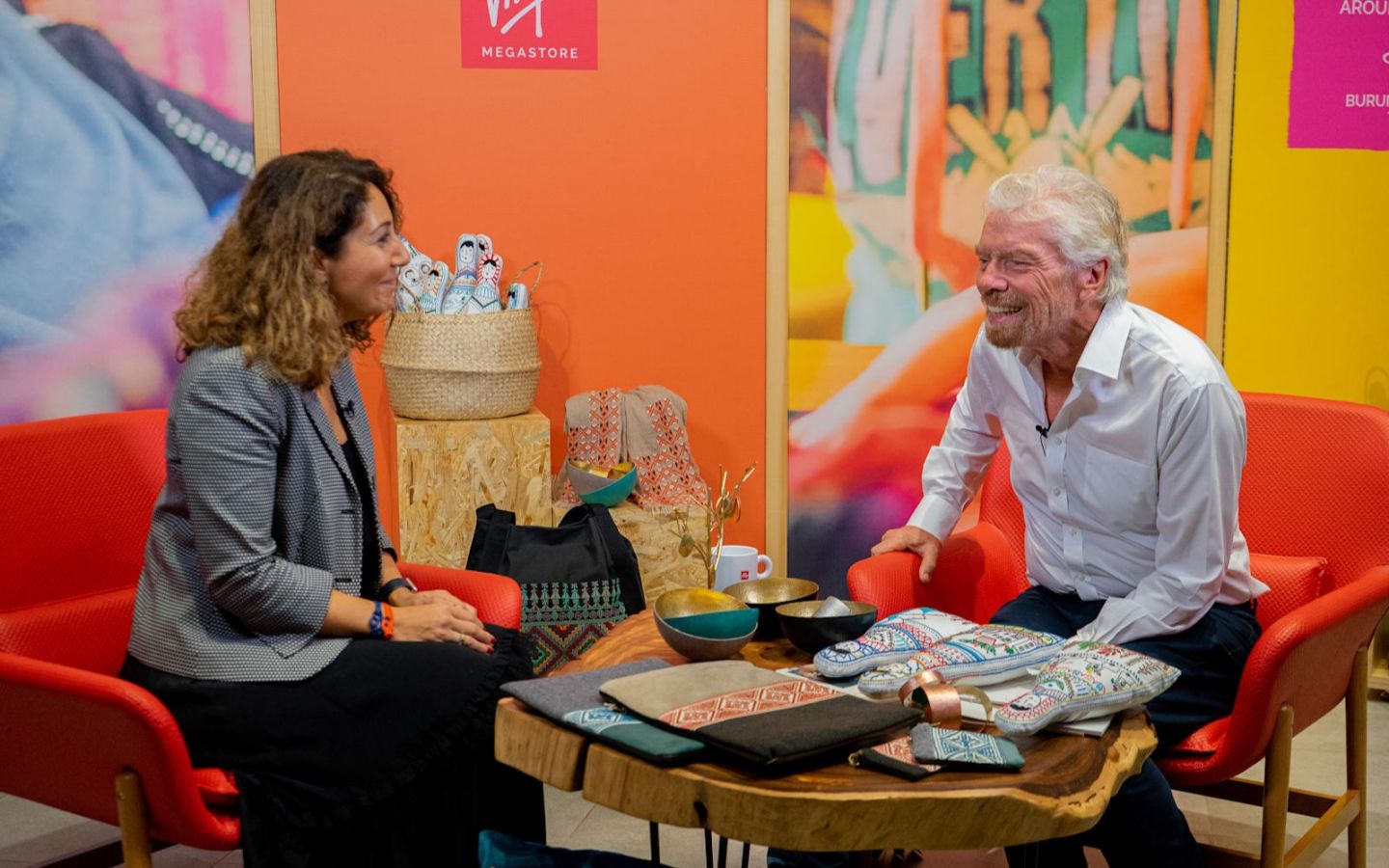 Richard Branson sat down with a lady laughing with a table of stock in front of them for Virgin Megastore in Dubai