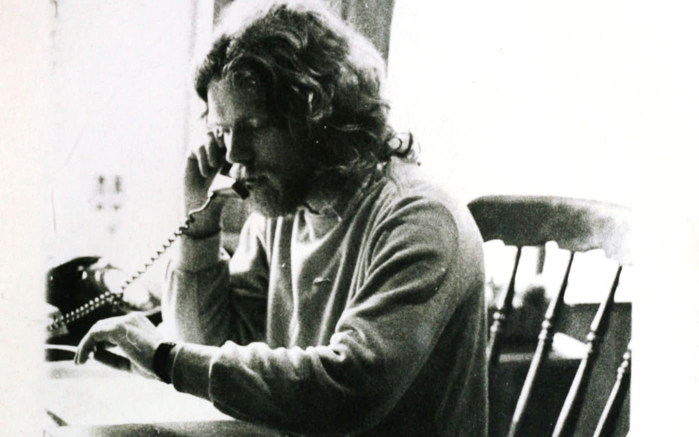 Black and white photo of Richard Branson in his 20s, sat at a desk, on the phone
