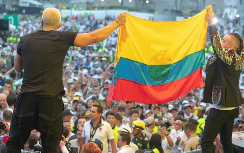 Two people on a stage hold up a Venezuelan flag to the audience