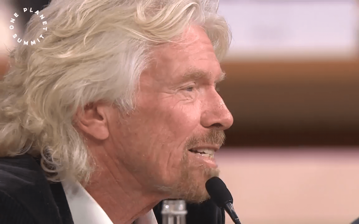 Richard Branson speaking into a microphone at the One Planet Summit